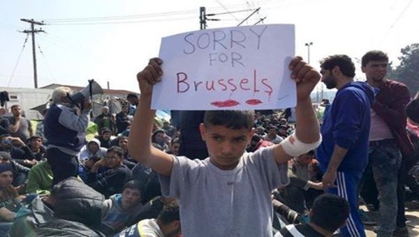 Cerca de Inomeni, Grecia, un niño refugiado sostiene un papel que dice: Lo sentimos por Bruselas.