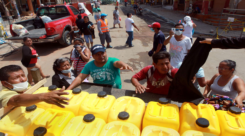 Un grupo de personas recibe insumos y agua de un camión con ayuda en Manta (Ecuador). 