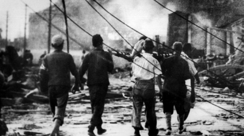 Momentos en el que trabajadores japoneses llevaban a una víctima del bombardeo atómico de Hiroshima.