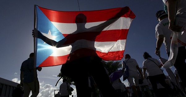A protester holding Puerto Rico’s flag takes part in a march to improve health care benefits in San Juan, Puerto Rico