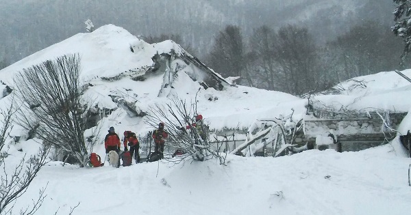 Members of Lazio's Alpine and Speleological Rescue Team stand in front of the Hotel Rigopiano in Farindola, central Italy, hit by an avalanche, Jan. 19, 201