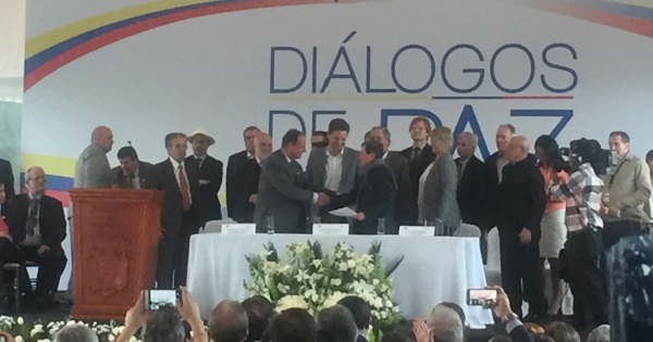 Lead negotiators from the ELN and the Colombian government shake hands.