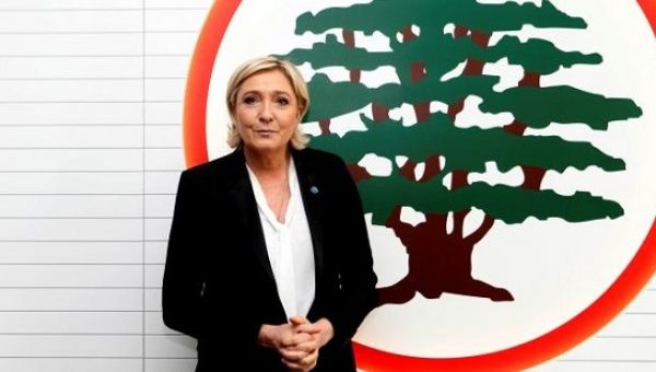 Marine Le Pen stands in front of the logo of the Christian Lebanese Forces party, Maarab, Lebanon Feb. 21, 2017.