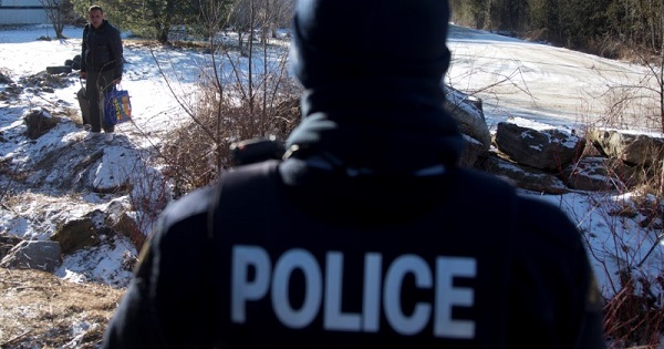 A man is confronted by a Royal Canadian Mounted Police officer as he prepares to cross the U.S.-Canada border leading into Hemmingford, Quebec.