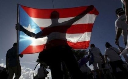 A protester holding a Puerto Rico's flag takes part in a march to improve health care benefits in San Juan, Puerto Rico, Nov. 5, 2015.