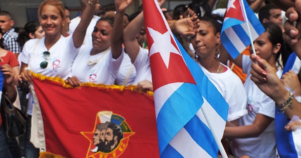 Cuban youth hold national flags and a Young Communist League banner.