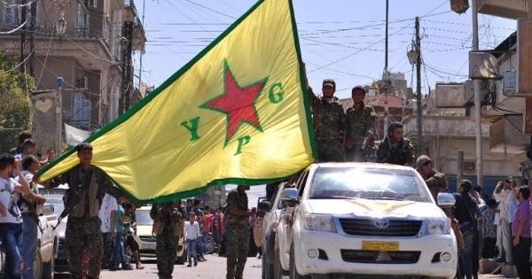 Kurdish People's Protection Units (YPG) fighters wave their flag in northeastern Syrian town of Qamishli.