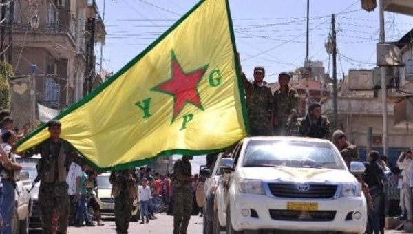 Kurdish People's Protection Units (YPG) fighters wave their flag in northeastern Syrian town of Qamishli. 