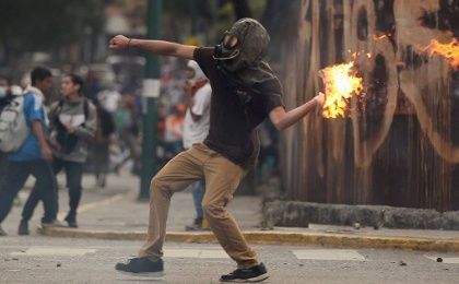 A demonstrator throws a Molotov cocktail during clashes with police in Caracas, Venezuela, amid protests.