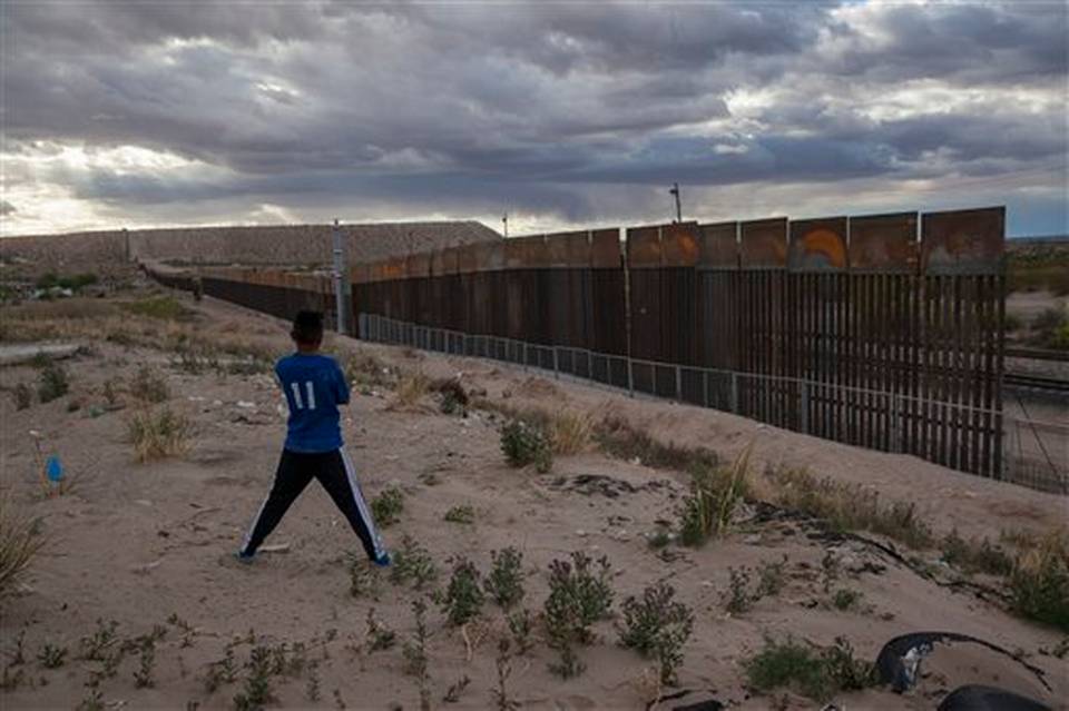 Un joven observa cerca que levantan a a lo largo de la frontera entre México y Estados Unidos.