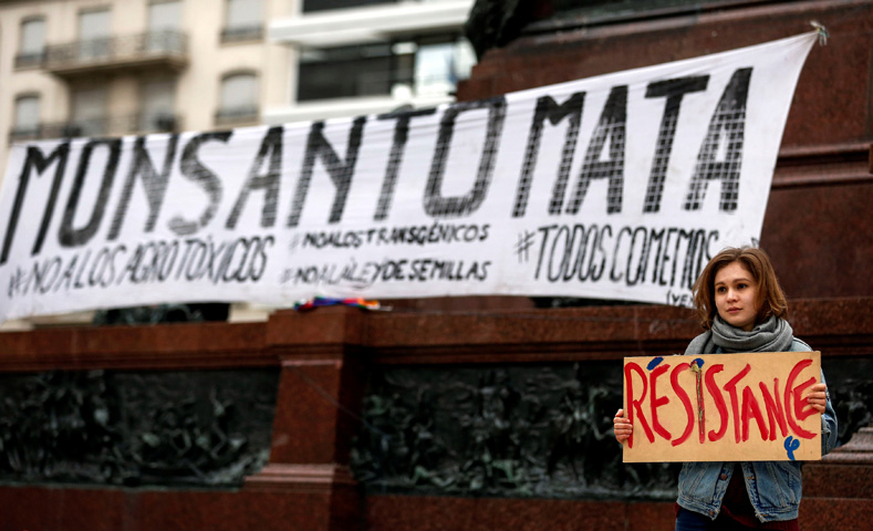 A demonstrator holds a sign in front of a banner that reads 