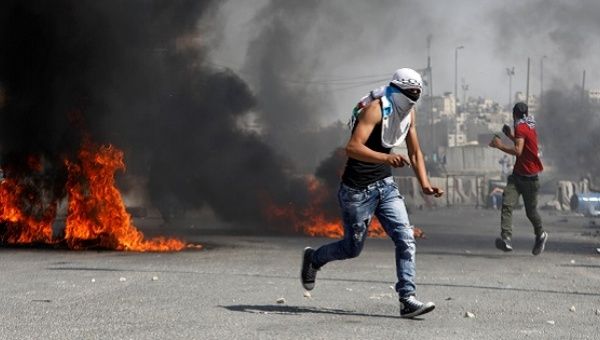 A Palestinian protester runs for cover during clashes with Israeli troops at a protest in support of Palestinian prisoners on hunger strike in Israeli jails.