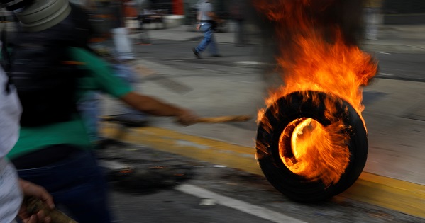 A tire is set to fire by opposition protesters, May 31, 2017.