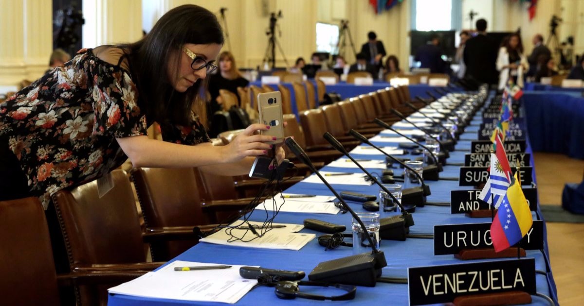 A woman takes pictures of delegates seats before the Organization of American States (OAS) meeting of foreign ministers to discuss the situation in Venezuela in Washington, U.S., May 31, 2017.