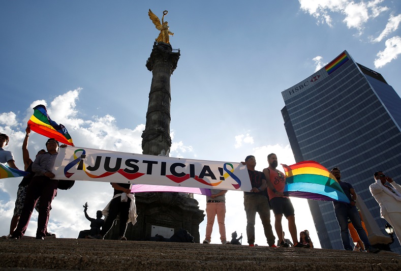 Members of the LGBT community hold up rainbow flags and a banner during a protest against the constant discrimination and violence against their community at the Angel of Independence monument in Mexico City, Mexico, June 23, 2017.