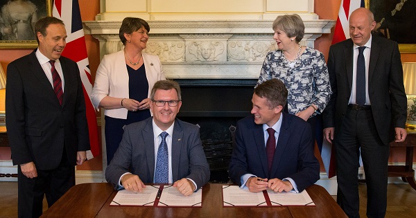 Prime Minister Theresa May next to DUP leader Arlene Foster, as DUP MP Jeffrey Donaldson signs paperwork with Britain's Parliamentary Secretary to the Treasury, Gavin Williamson.