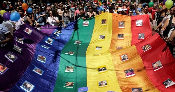 Marchers hold a rainbow flag with photos of the victims of the Orlando shooting at San Francisco LGBTQ Pride, June 26, 2016.