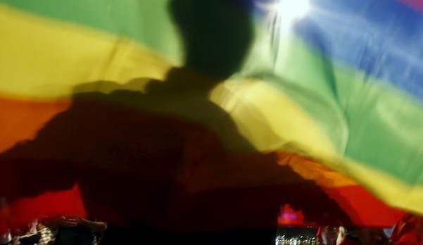 A man is silhouetted on a rainbow flag during a demonstration for LGBTI rights.