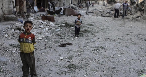 Children stand in the rubble of destroyed buildings in Syria.