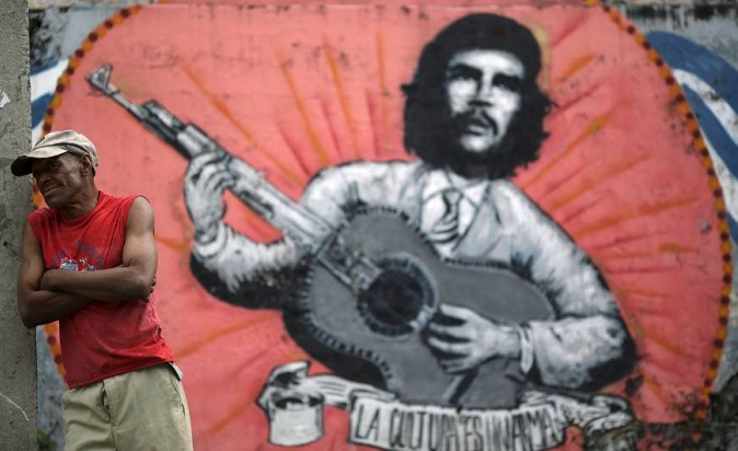 A man stands next to a mural of Ernesto 'Che' Guevara