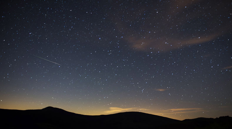 Una Lágrima de San Lorenzo atraviesa el cielo junto a la Vía Láctea esta madrugada, sobre el municipio cántabro de San Miguel de Aguayo, en una de las noches de máxima actividad de este fenómeno producido al atravesar la tierra la trayectoria del cometa Swift-Tuttle.