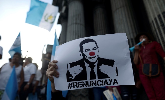 A demonstrator holds a sign as he protests against Guatemalan President Jimmy Morales in front of the National Palace in Guatemala City.