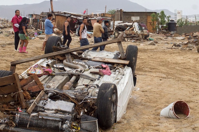 Residents walk past damaged vehicles in the aftermath of Tropical Storm Lidia in Los Cabos, Mexico.