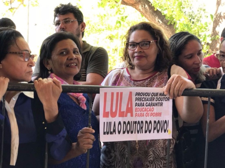 People awaiting Lula's arrival hold a sign that reads, 