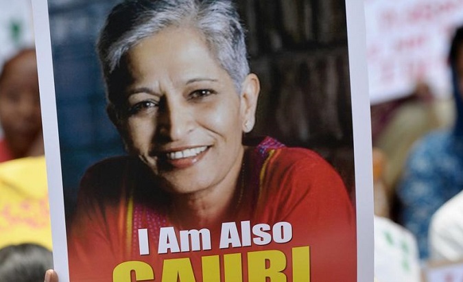 A protester holds a sign with journalist Gauri Lankesh at a rally following her murder on Tuesday night.