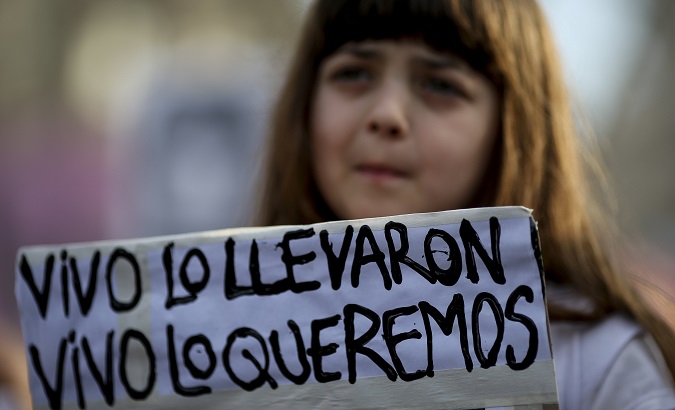 A woman holds a sign that reads, 