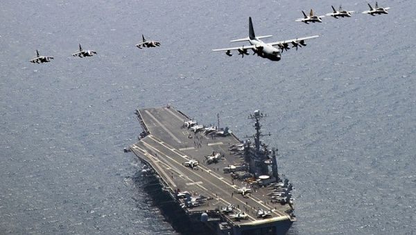 A U.S. Marine Corps C-130 Hercules aircraft leads a formation over the aircraft carrier USS George Washington in the East Sea of Korea.