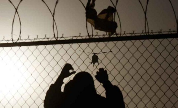 A man watches a U.S. border patrol helicopter from a fence at the border between Mexico and the United States, in Ciudad Juarez March 8, 2012.