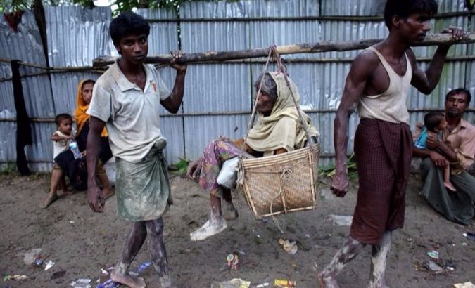 Rohingya men carry their sick mother in the streets as they arrive at Bangladesh border at Teknaf, Bangladesh.
