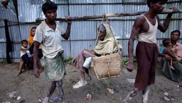 Rohingya men carry their sick mother in the streets as they arrive at Bangladesh border at Teknaf, Bangladesh.