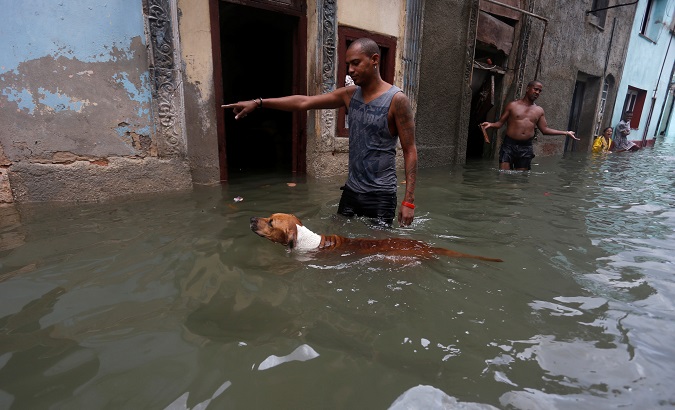 A man gestures to his dog on a flooded street in Havana