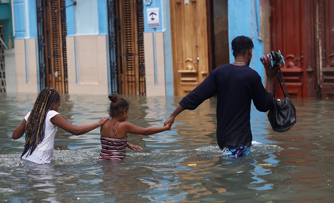 A man and two children wade through a flooded street, after Hurricane Irma, in Havana