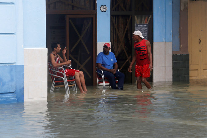 People sit in a flooded street