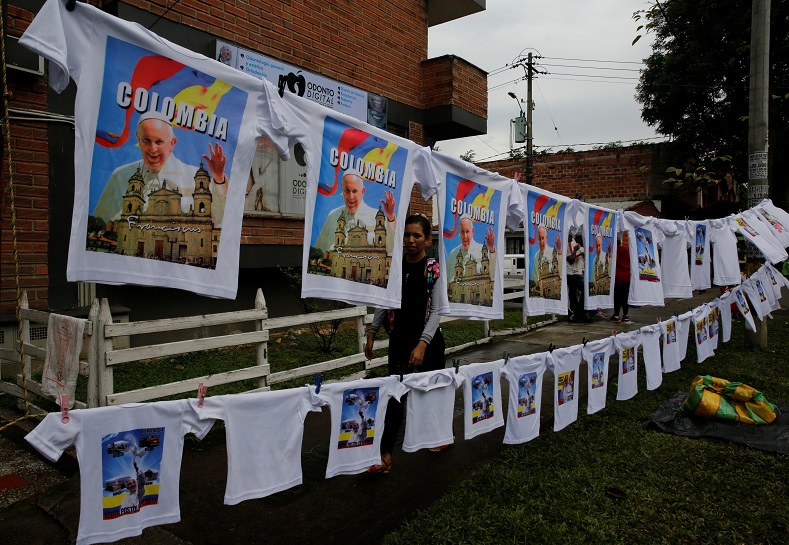 A woman sells T-shirts with images of the pope as people arrive for a mass outside Olaya Herrera Airport, Medellin, Colombia, Sept. 9, 2017.