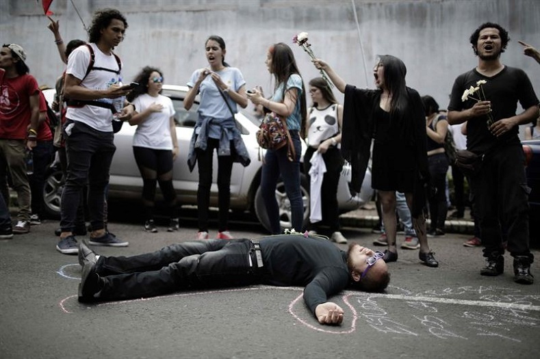 A student depicting a dead body lies on the ground at a protest in San Jose on September 12, 2017.