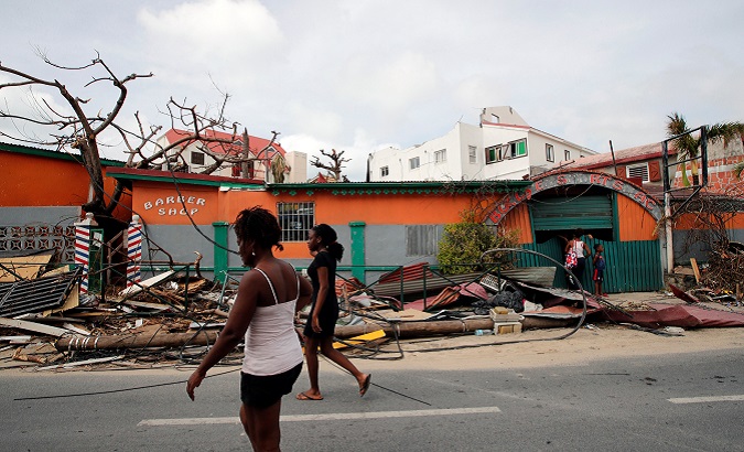 Residents walk in front of houses destroyed by Hurricane Irma during the visit of France's President Emmanuel Macron in St Martin.