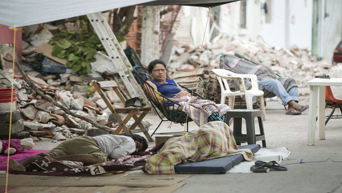 Las personas duermen a las afueras de sus casas destruidas por el terremoto que ahora serán demolidas.