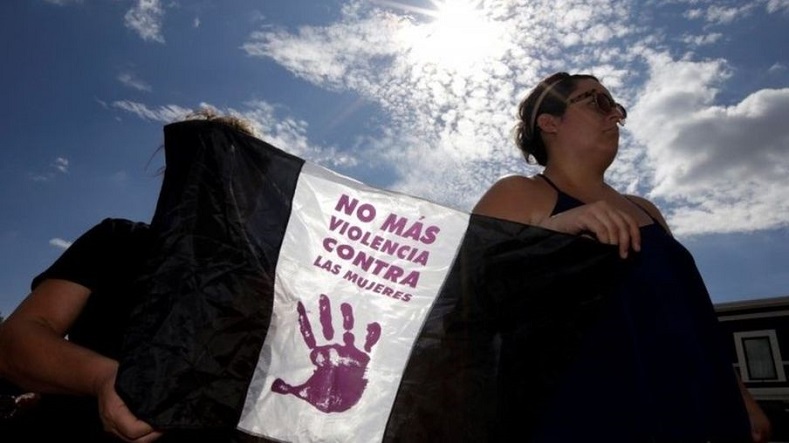 Women hold a banner that reads, 
