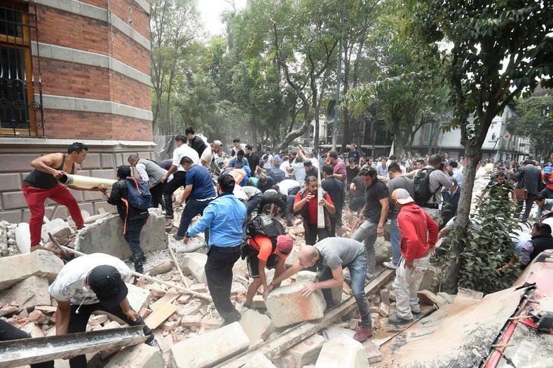 People remove debris of a damaged building after an earthquake hit Mexico City.