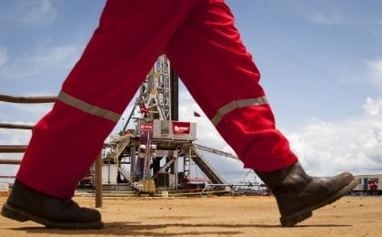 An oil worker walks past a drilling rig at an oil well operated by Venezuela's state oil company PDVSA in Morichal July 28, 2011.