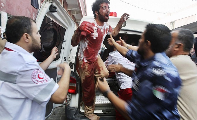 A Palestinian man cries in clothes stained with the blood of his father, who medics said was killed by Israeli shelling
