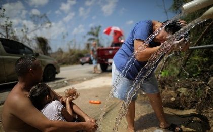 A resident washes her hair with water from a pipe on the side of a road days after Hurricane Maria hit Puerto Rico.