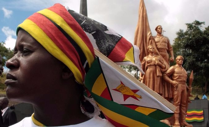 A Zimbabwean woman stands in front of a statue depicting national heroes.