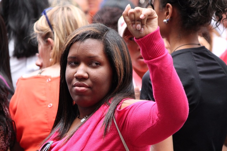 A woman raises her fist while marching against U.S.-backed economic war in Venezuela.