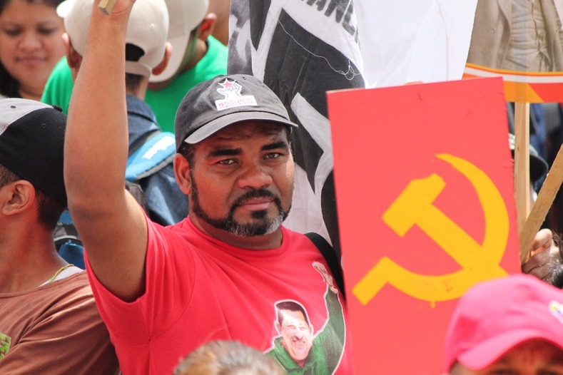 A man wearing a shirt displaying former Venezuelan president Hugo Chavez celebrating the Bolshevik revolution.