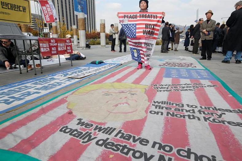 A South Korean protester stands on a cartoon depiction of US President Donald J. Trump during a rally held to show opposition to the US President's upcoming visit to South Korea, in front of the U.S. embassy in Seoul, South Korea, Nov. 6, 2017.